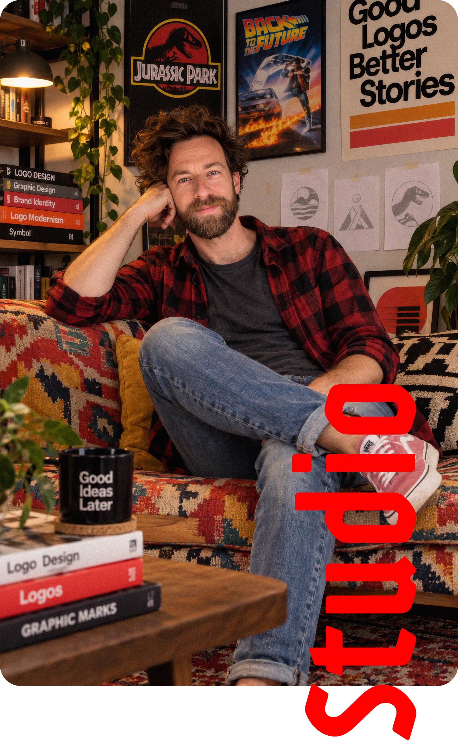 Bertrand Dejean, fondateur du studio Karmmma, assis dans un fauteuil de son atelier, entre croquis de logos, nuanciers et monogramme rouge
